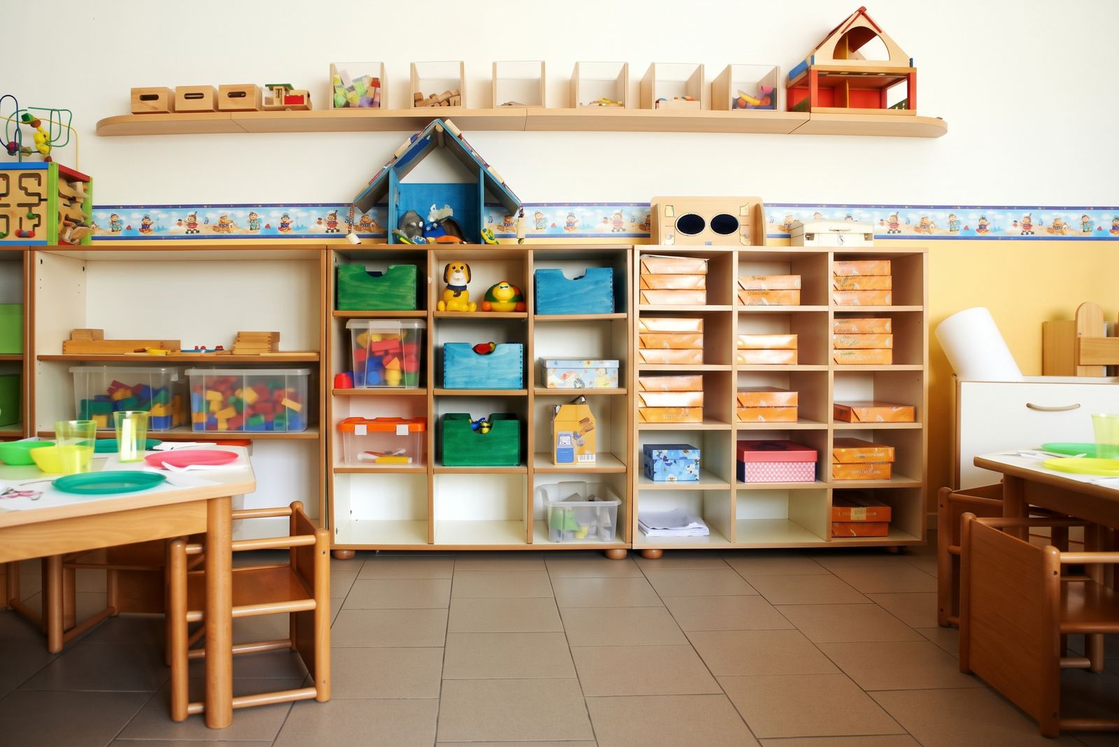 L'aula con scaffali pieni di giochi, scatole colorate e tavolini a misura di bambino