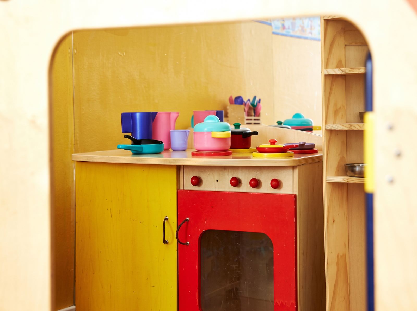Una cucina giocattolo in legno con pentole e tazze colorate